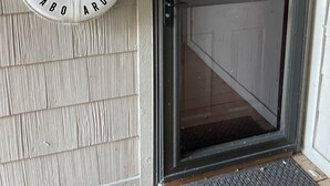 Une porte avec un panneau de verre, une pancarte de bienvenue et une sonnette au mur.