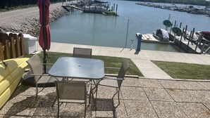 Un espace extérieur aménagé avec une table et des chaises, donnant sur une marina où sont amarrés des bateaux.