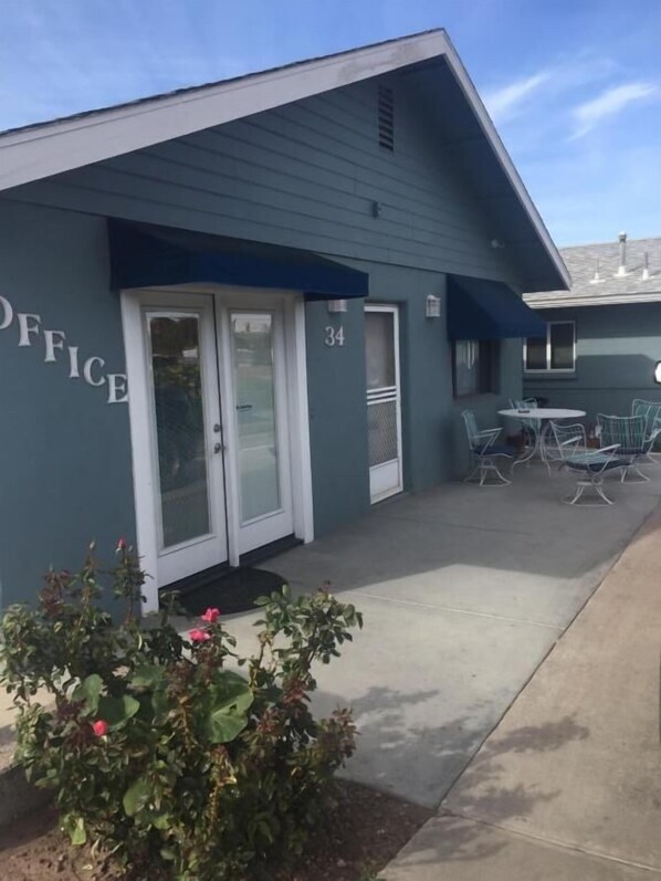 A building with a sign reading "OFFICE" and the number "34" on the door. There is a patio area with outdoor seating.