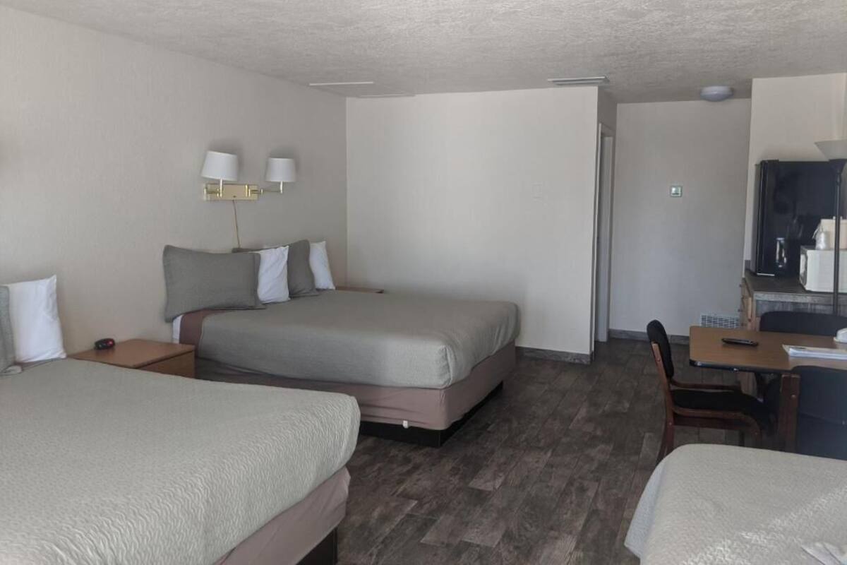 A hotel room with two beds, a desk, and a chair.