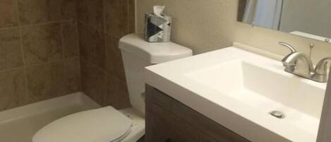 A bathroom with a toilet, a sink, and a shower area.