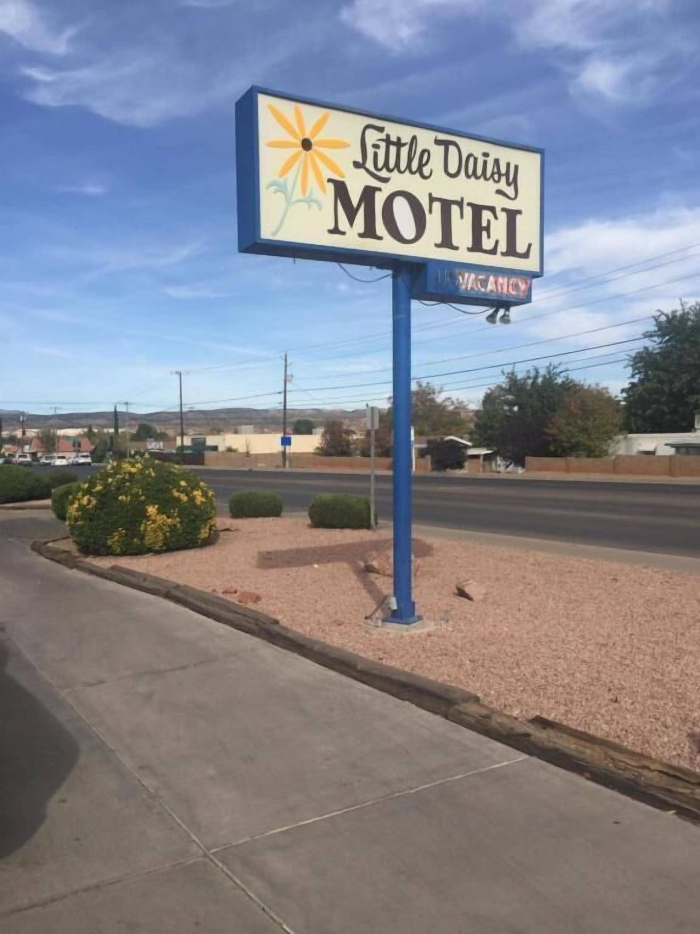 Letrero de motel con diseño de sol y flor, que indica disponibilidad.