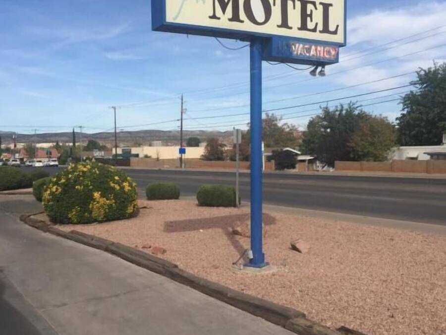 Letrero de motel con diseño de sol y flor, que indica disponibilidad.