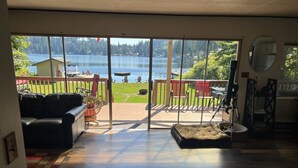 Una habitación con puerta de vidrio corredera que da a una terraza con vistas a un lago y un bosque.