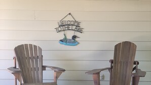 Dos sillas Adirondack de madera enfrentadas, con un cartel que dice 'Welcome to Lochlea' arriba.