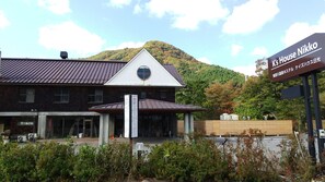 Un edificio con un cartel que dice "K's House Nikko" y una montaña al fondo.