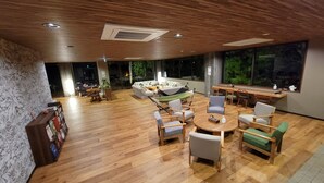 Amplia sala de estar con suelo de madera, un sofá, varias sillas y una mesa de comedor.