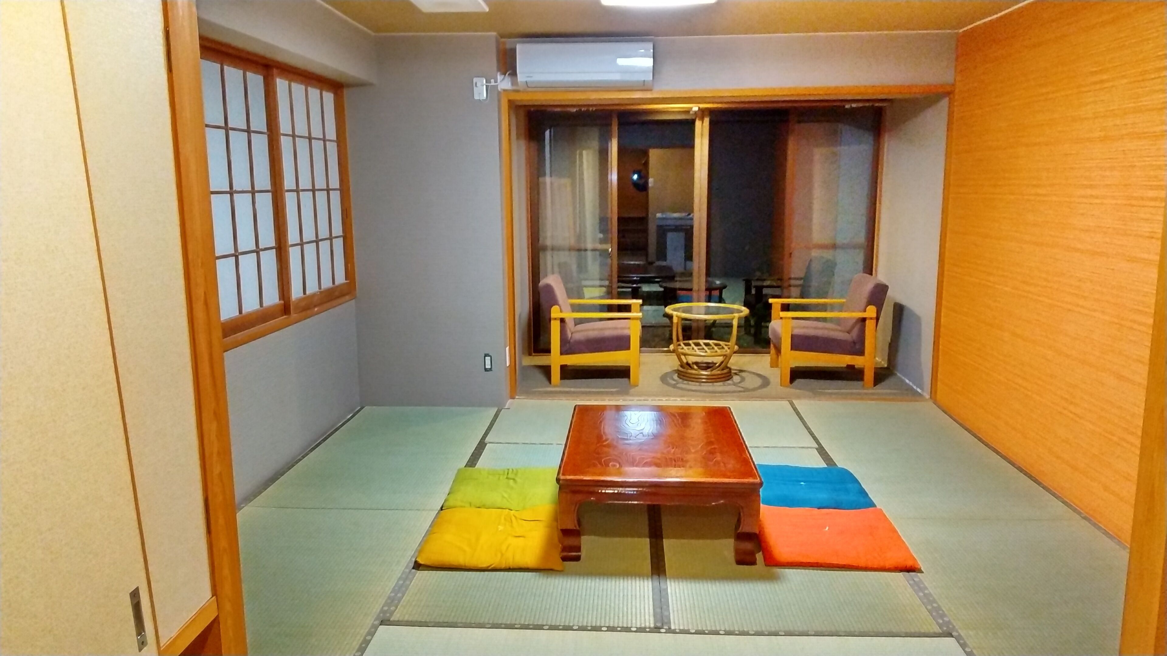 A traditional Japanese room with tatami flooring, a low wooden table, and two chairs.