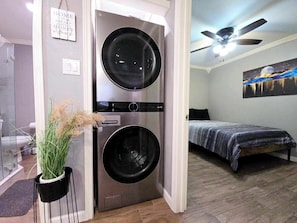 Ein kleines Zimmer mit einem Bett, einem Deckenventilator und einer fest installierten Waschmaschine und einem Trockner.