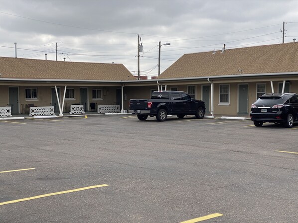 A motel with two parking spaces, a black pickup truck, and a black sedan parked in front.