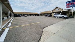 Un motel doté d’un parking, de plusieurs chambres et d’un panneau indiquant des tarifs avantageux et des tarifs hebdomadaires.