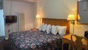 Une chambre d ’hôtel comprenant un lit, deux lampes de chevet, un téléviseur fixé au mur, une chaise et un bureau.