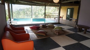 A room with a checkered floor, a pool, and orange chairs. - Fazenda Pedra Riscada (Nova Friburgo)
