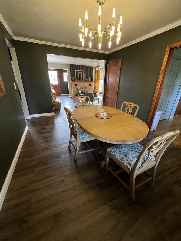 A dining area with a round wooden table, six chairs, and a chandelier. - Mid-Century Modern Home (Washington)