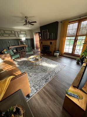 A spacious living room with a fireplace, leather sofa, and a large rug. - Mid-Century Modern Home (Washington)
