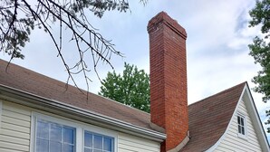 A white building with a brick chimney, large windows, and a black wrought iron fence. - Mid-Century Modern Home (Washington)