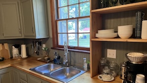 A kitchen with a double sink, wooden countertops, and a window with a view of greenery. - Mid-Century Modern Home (Washington)