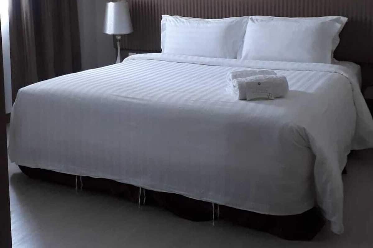 Ein Hotelzimmer mit einem großen Bett, einer Nachttischlampe und Blick ins Freie.