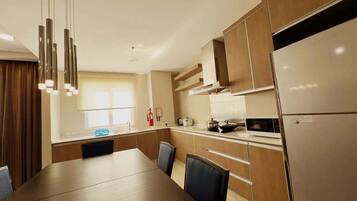 Una cocina moderna con comedor, que incluye electrodomésticos de acero inoxidable, armarios de madera e iluminación colgante.
