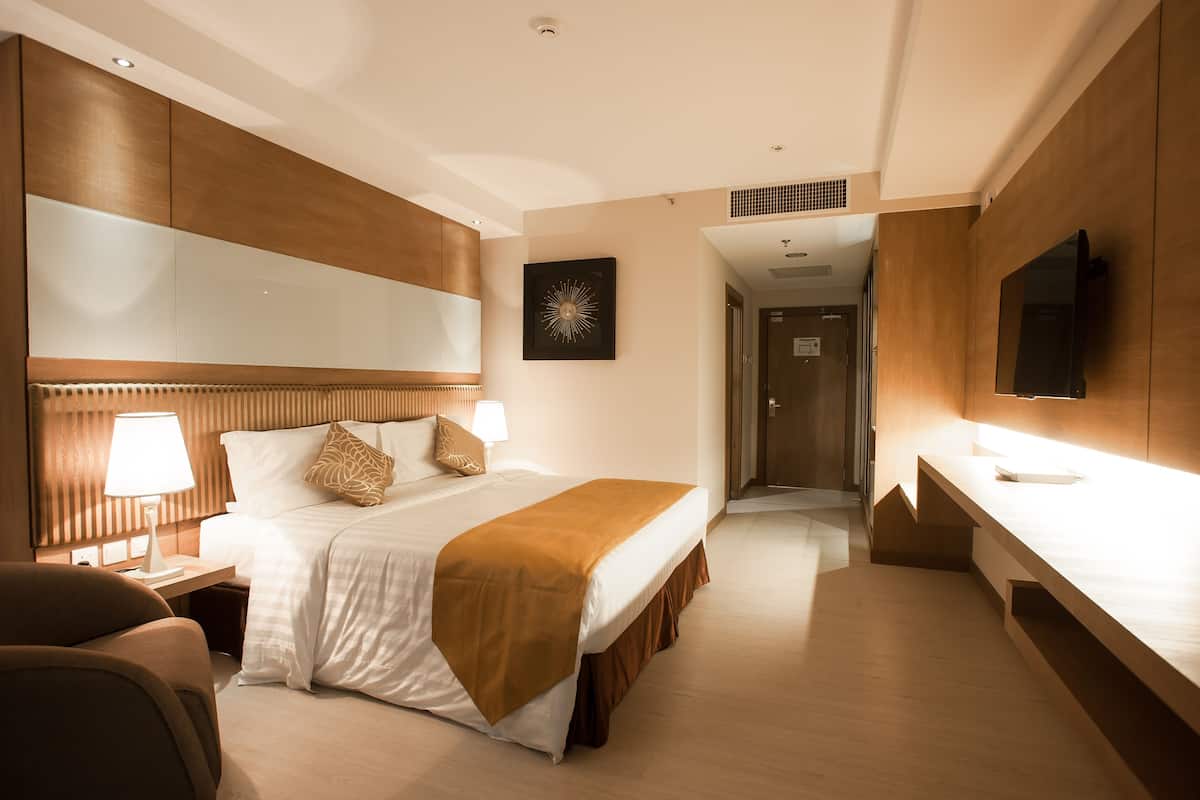 Ein modernes Hotelzimmer mit einem großen Bett, Nachttischlampen, einem Flachbildfernseher und einem Holzkopfstück.