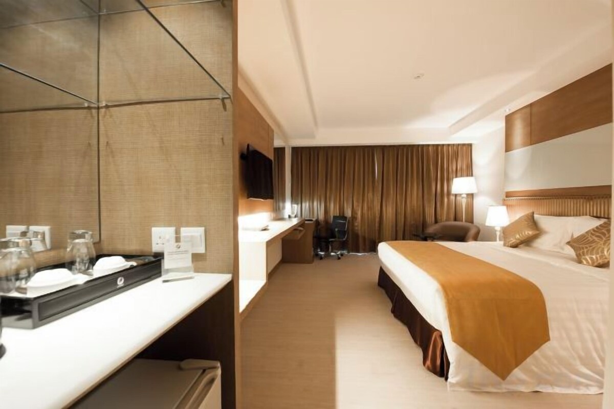 A hotel room with a bed, bedside table, lamp, and a television.
