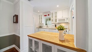 A kitchen with white cabinets, a wooden countertop, and a microwave. - Stylish villa in the heart of all fun in Miami (Miami)