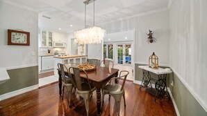 A dining area with a wooden table and chairs, a chandelier, and a clock on the wall. - Stylish villa in the heart of all fun in Miami (Miami)