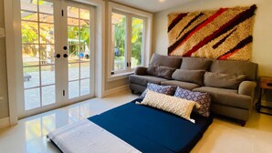 A modern living room with a sofa, a large rug, and a view through glass doors to an outdoor area. - Stylish villa in the heart of all fun in Miami (Miami)