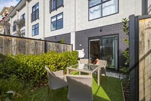 Un bâtiment moderne doté d’un patio aménagé avec des meubles en osier et une petite table.