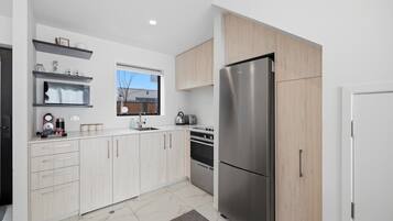 A modern kitchen with a stainless steel refrigerator, a built-in oven, and a window above the sink.