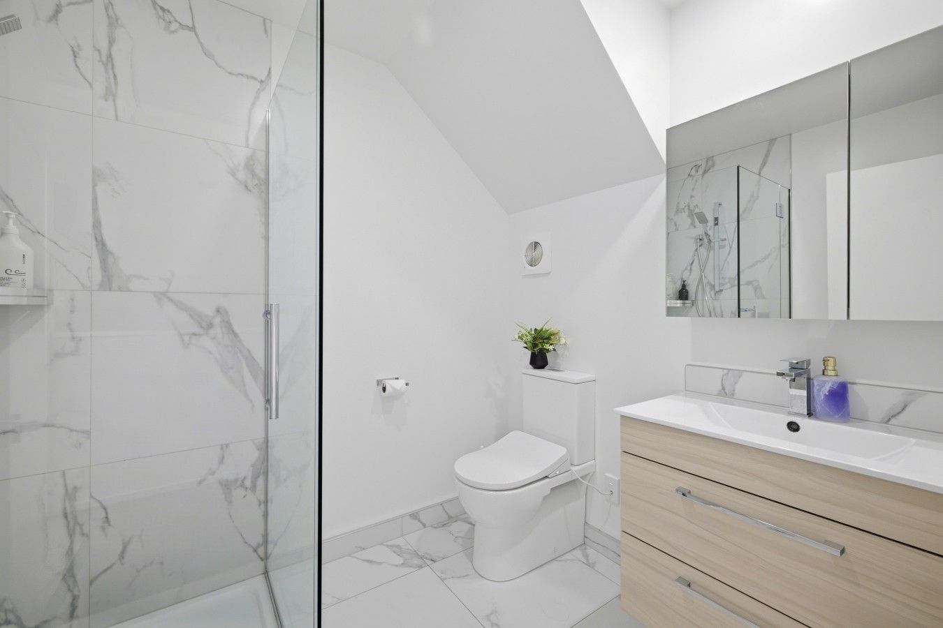 Une salle de bain moderne avec une douche à parois de verre, des toilettes, un lavabo avec un miroir et des meubles en bois.