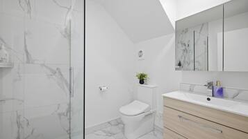 Une salle de bain moderne avec une douche à parois de verre, des toilettes, un lavabo avec un miroir et des meubles en bois.