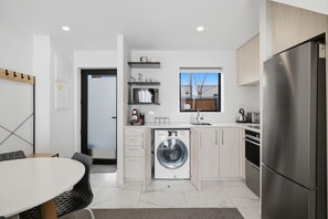 Une cuisine moderne équipée d’un lave-linge intégré, d’un réfrigérateur et d’un coin repas avec une table et des chaises.