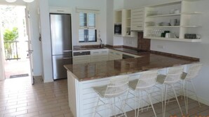 Una cocina moderna con una isla central, armarios blancos y un refrigerador de acero inoxidable.