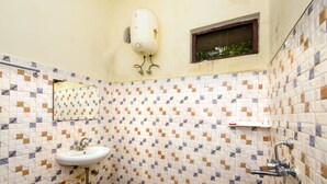 Une salle de bain avec un sol carrelé, un lavabo, un miroir, un radiateur et une fenêtre.