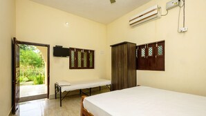 Une chambre d’hôtel comprenant un lit, une armoire, une télévision et une porte donnant sur un jardin.