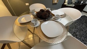 Ein Esstisch ist mit weißen Tellern, Tassen und einem dekorativen Mittelstück gedeckt.