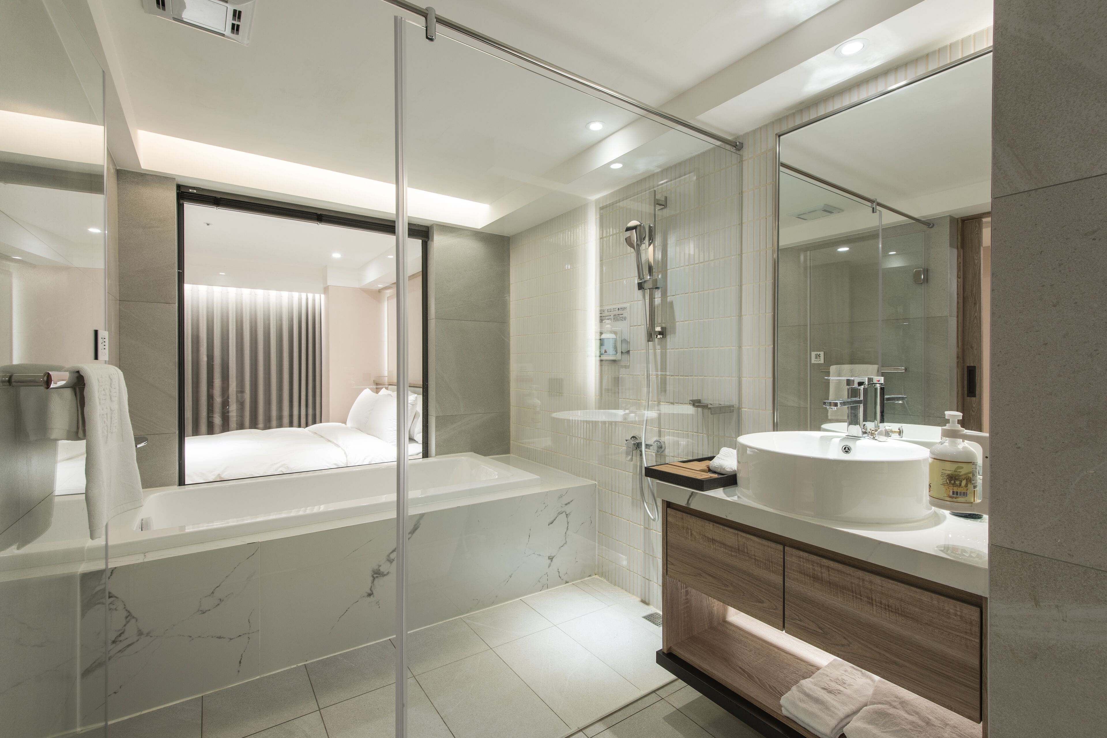 A modern bathroom with a glass-enclosed shower, a large bathtub, and a vanity with a sink and mirror.