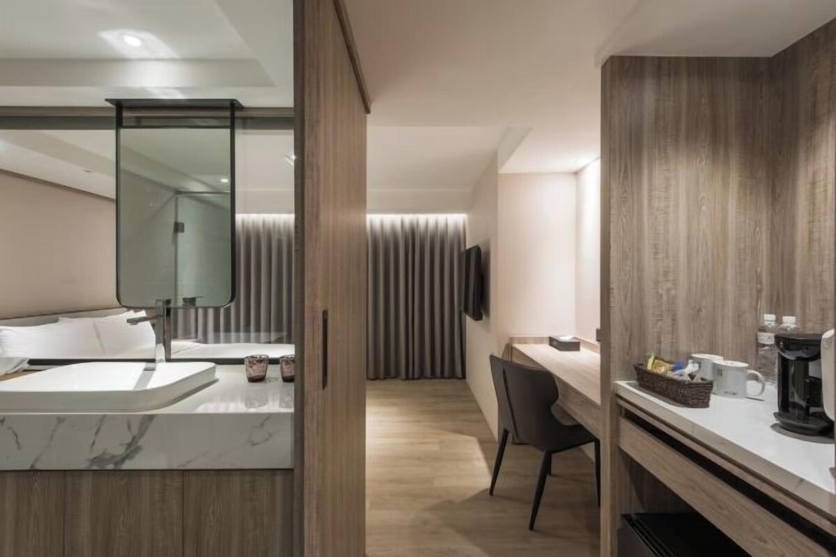 A modern bathroom with a marble sink, a large mirror, and a shower area.