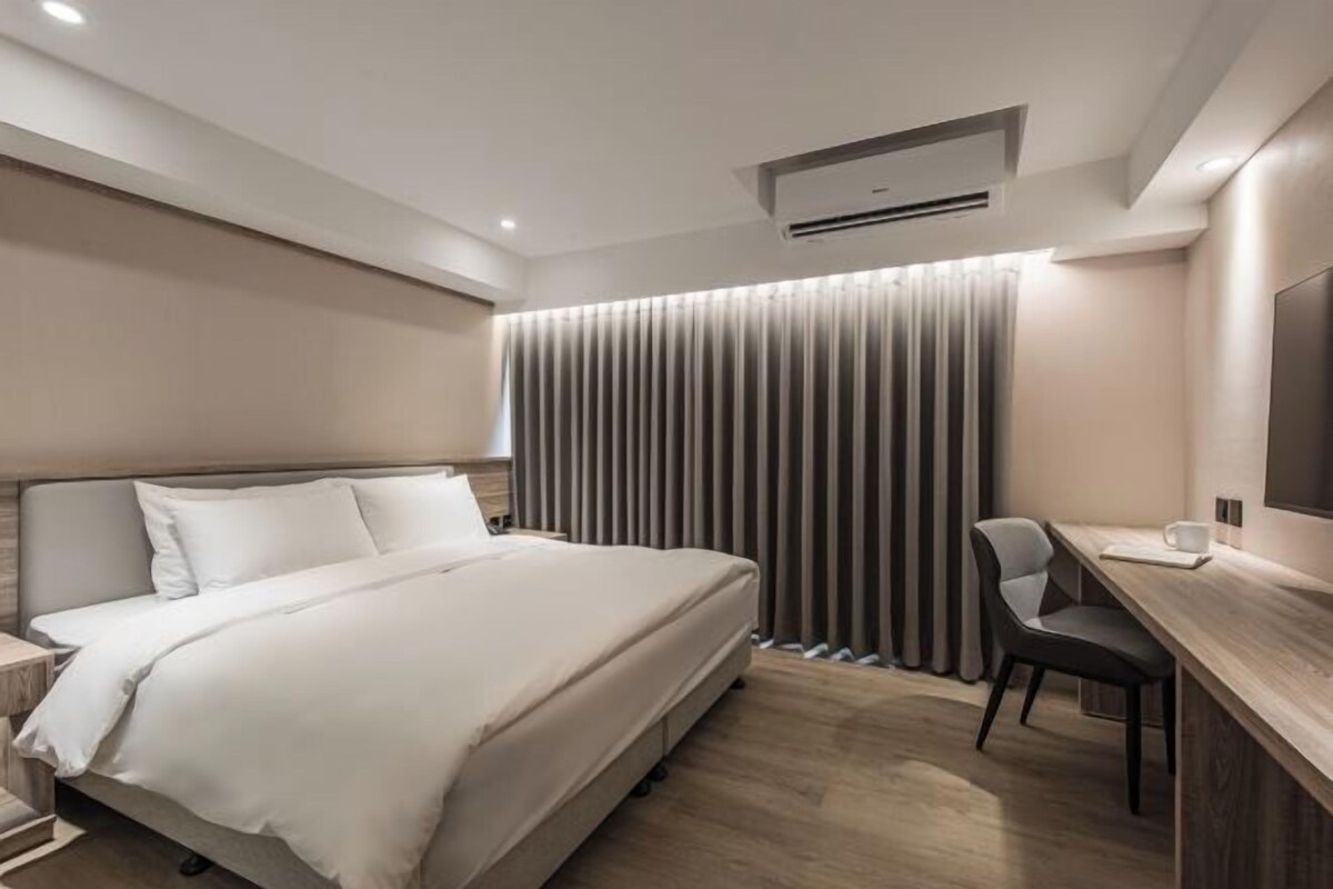 Una habitación de hotel moderna con una cama grande, un escritorio y una silla.