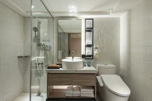 A modern bathroom with a glass-enclosed shower, a wooden vanity, a white sink, and a toilet.
