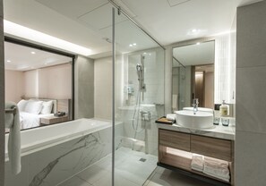 A modern bathroom with a glass-enclosed shower, a large marble bathtub, and a vanity with a sink and mirror.