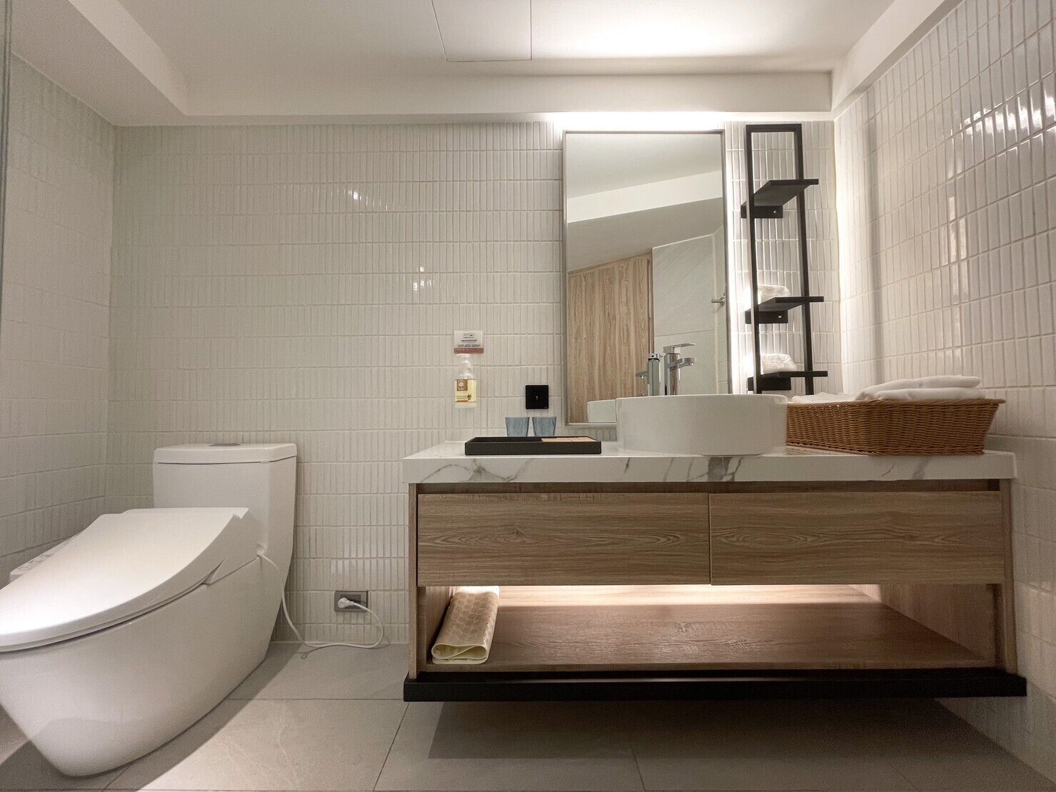 A modern bathroom with a toilet, sink, and mirror.