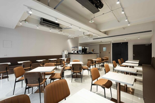 A modern dining area with multiple tables and chairs, an air conditioning unit, and a counter with a coffee machine. - Spring's Rhapsody Hotel (Taichung)