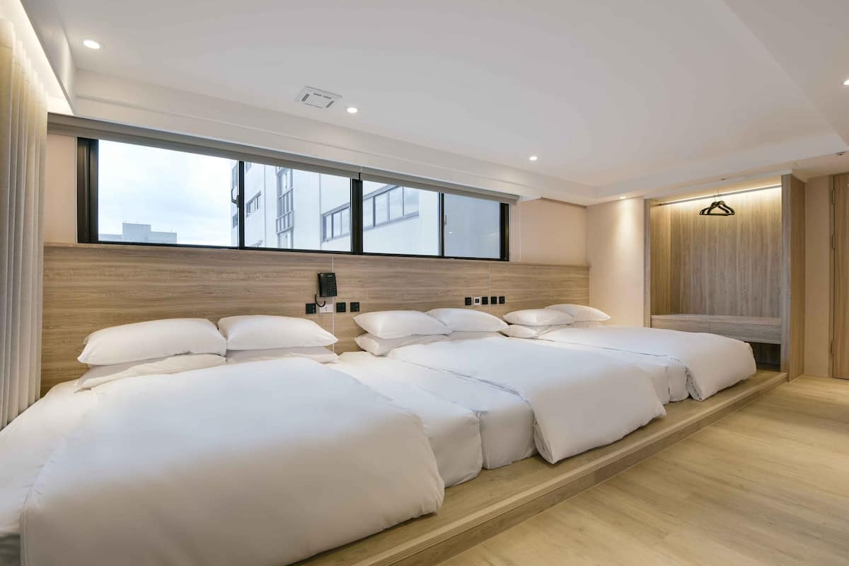 Ein modernes Hotelzimmer mit einem großen Bett, einem Holzkopfschild, einem großen Fenster und einer hängenden Leuchte.