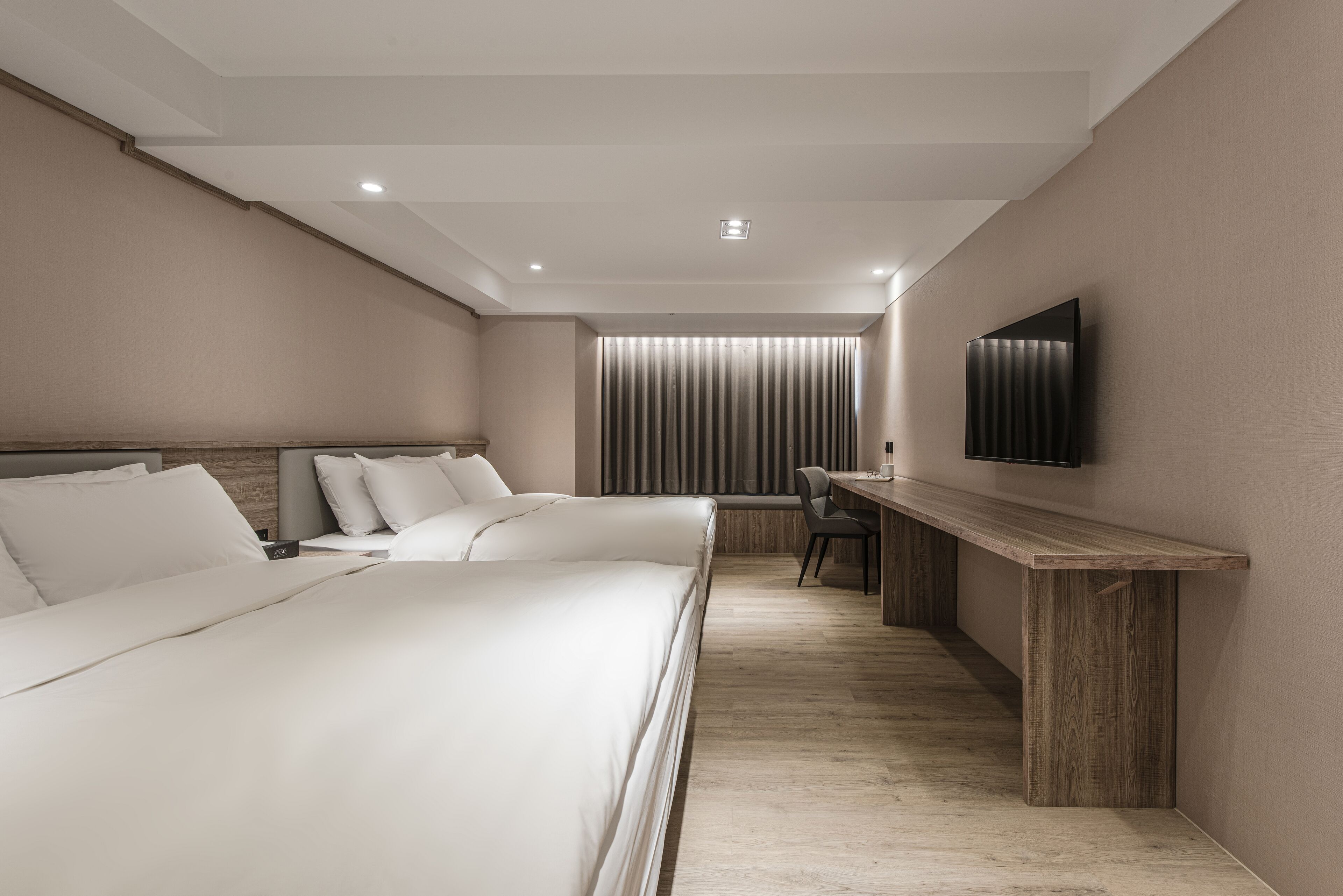 A modern hotel room with a large bed, a desk, and a TV mounted on the wall.