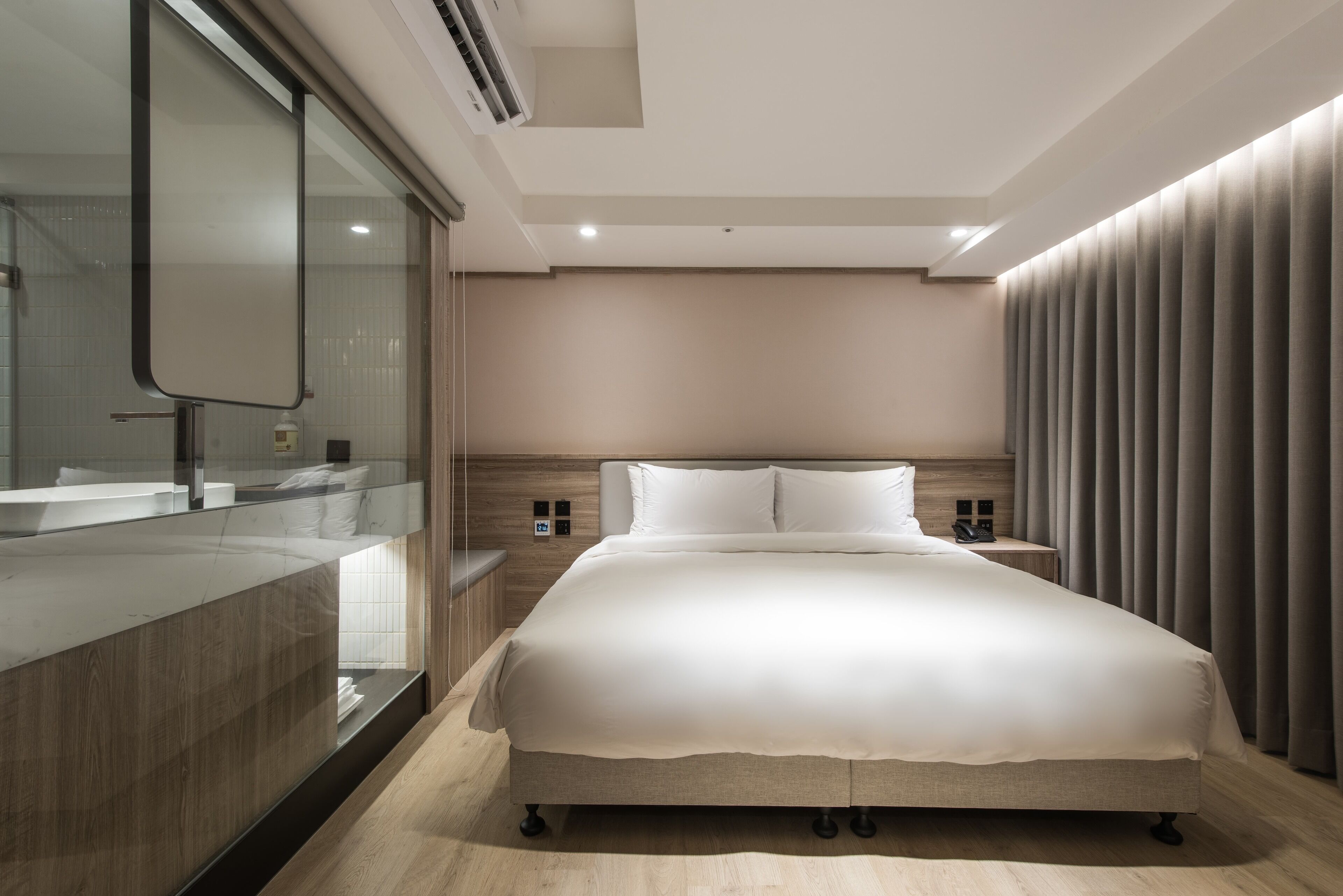 Una habitación de hotel moderna con una cama grande, un tocador integrado y un amplio ventanal.