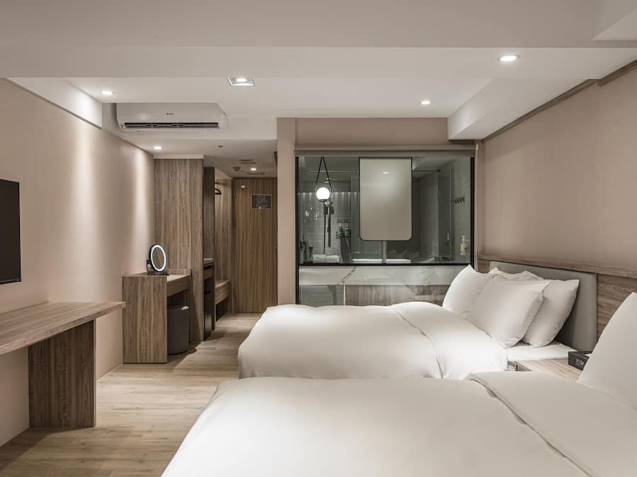 A modern hotel room with a large bed, a desk, and a TV.