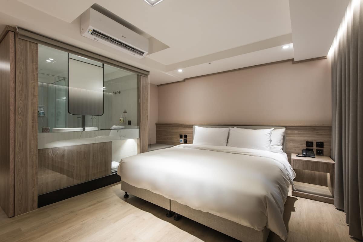 Ein modernes Schlafzimmer mit einem großen Bett, einem Einbauschrank und einem Nachttisch mit Telefon und Ladegerät.