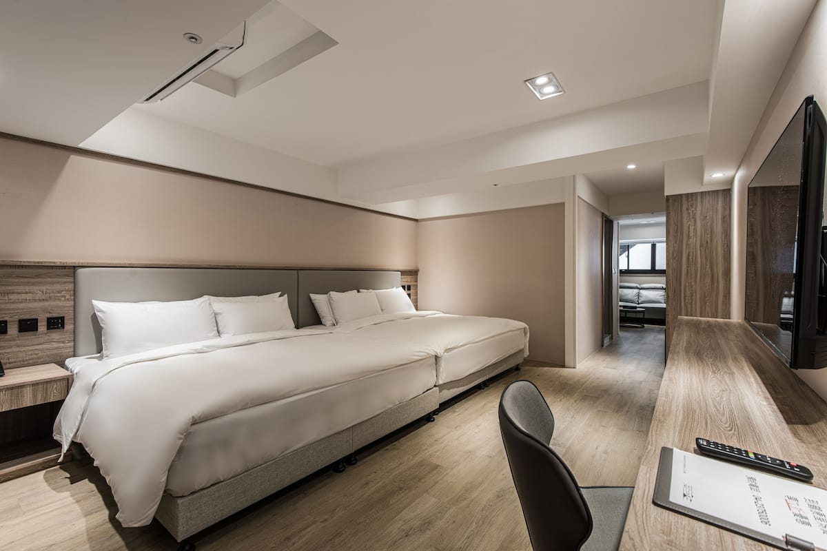 Ein modernes Hotelzimmer mit einem großen Bett, einem Schreibtisch mit Stuhl und einem Flachbildfernseher.